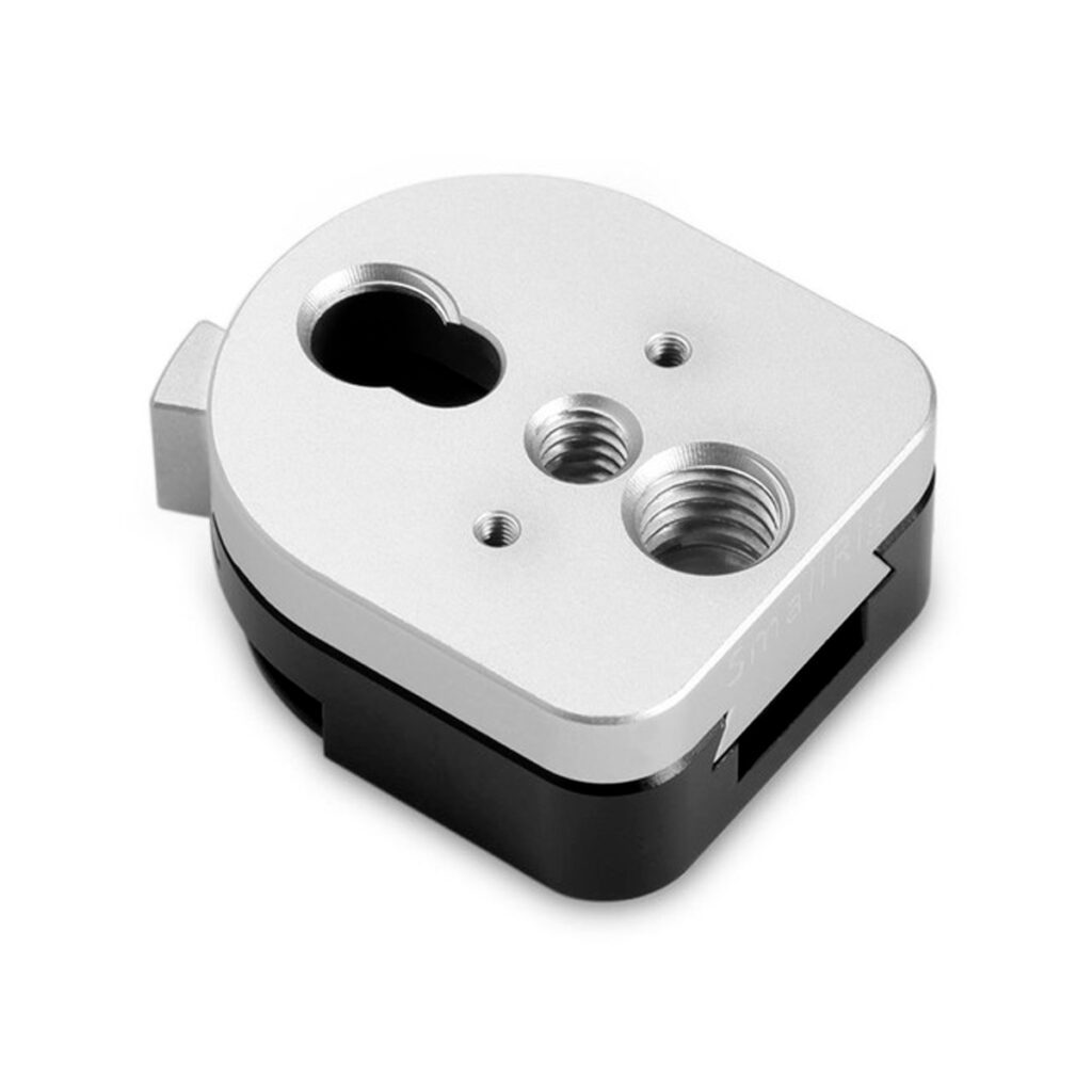 SmallRig-1855 Lähikuvassa SmallRig 1855 QR Mount Device S-Lock, metallinen, pyöristetty suorakulmainen komponentti, jossa on hopea ja musta viimeistely, useita kierrereikiä ja aukkoja.