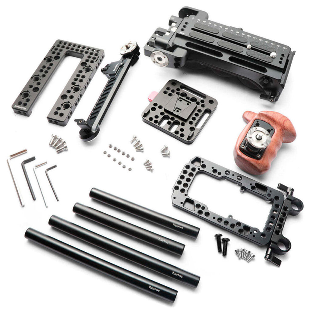 SmallRig-2045-2 SmallRig 2045 Pro Accessory Kit Sony FS7/FS7II:lle on esillä valkoisella pinnalla, ja siinä on metallisia kiinnityslevyjä, tankoja, ruuveja, kuusiokoloavaimia, puinen kahva ja erilaisia komponentteja kameran kokoonpanoon ja mukauttamiseen.