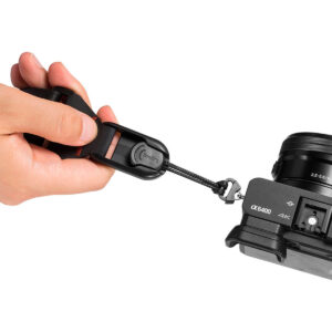 SmallRig-2428-6 Käsi kiinnittää SmallRig 2428 Camera Shoulder Strap -kamerahihnan pikakiinnityslukolla mustaan Sony Alpha α6400 -kameraan ja näyttää lähikuvan hihnan kiinnitysmekanismista.