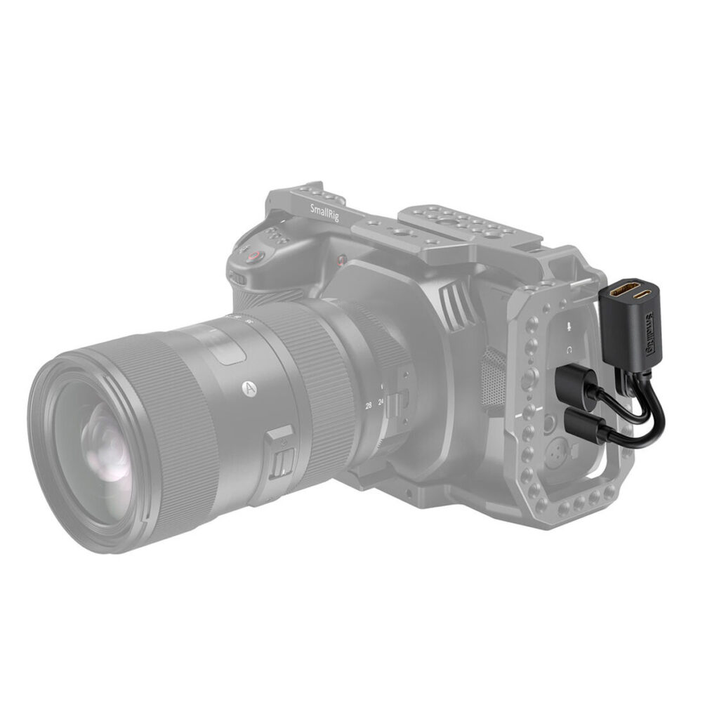 SmallRig-2960-2 Digitaalinen kamera häkki-rigissä on liitetty kahdella kaapelilla SmallRig 2960 HDMI & USB-C Adapter for BMPCC 4K & 6K Cage -laitteeseen, jossa on kaksi USB-porttia; sovitin näkyy täysvärisenä, kun taas kamera ja rig ovat harmaasävyisiä.
