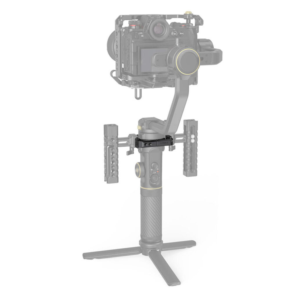 SmallRig-2994-4 SmallRig 2994 Mounting Clamp for Zhiyun Crane 2S on kuvassa kiinnitettynä kameran kardaaniin, jossa on kaksi sivukahvaa lisätukea varten. Vakaimessa on kuvioitu kahva, jossa on kultaisia korostuksia, ja se on kiinnitetty kolmijalkaiseen jalustaan.