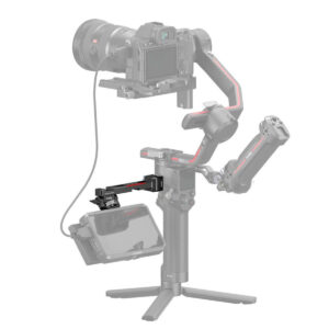 SmallRig-3026B-2 The picture shows a professional camera with a handheld gimbal and tripod on which an external monitor is mounted using the SmallRig 3026B Monitor Mount for DJI Ronin. Some parts of the mount appear semi-transparent grey.