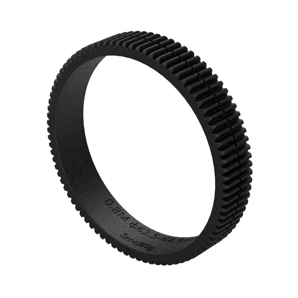 SmallRig-3291 SmallRig 3291 Focus Gear Ring Seamless 62,5-64,5 mm on musta, pyöreä rengas, jossa on tasaisin välein olevat hampaat ulkoreunalla, kuvattuna kulmassa valkoista taustaa vasten.