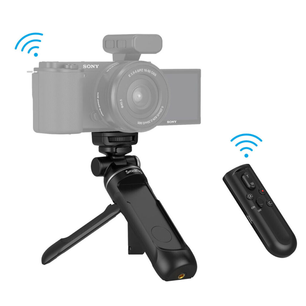 SmallRig-3326-6 SmallRig 3326 SR-RG1 langaton kuvauskahva, kuvassa digitaalikamera asennettuna mustalle pöytäjalustalleen ja irrotettavalla langattomalla kaukosäätimellä, jossa on siniset signaalikuvakkeet, jotka ilmaisevat etäyhteyden.