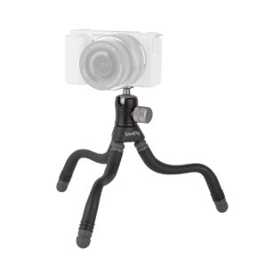 SmallRig 3446 BeautyPod 1.5K Flexible Mini Tripod BT-15:ssä on kolme taivutettavaa mustaa jalkaa ja hopeinen säätönuppi, jotka tukevat osittain läpinäkyvää peilitöntä kameraa.
