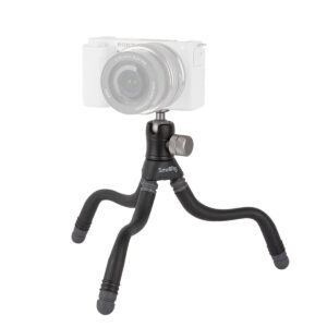 SmallRig-3446 SmallRig 3446 BeautyPod 1.5K Flexible Mini Tripod BT-15:ssä on kolme taivutettavaa mustaa jalkaa ja hopeinen säätönuppi, jotka tukevat osittain läpinäkyvää peilitöntä kameraa.