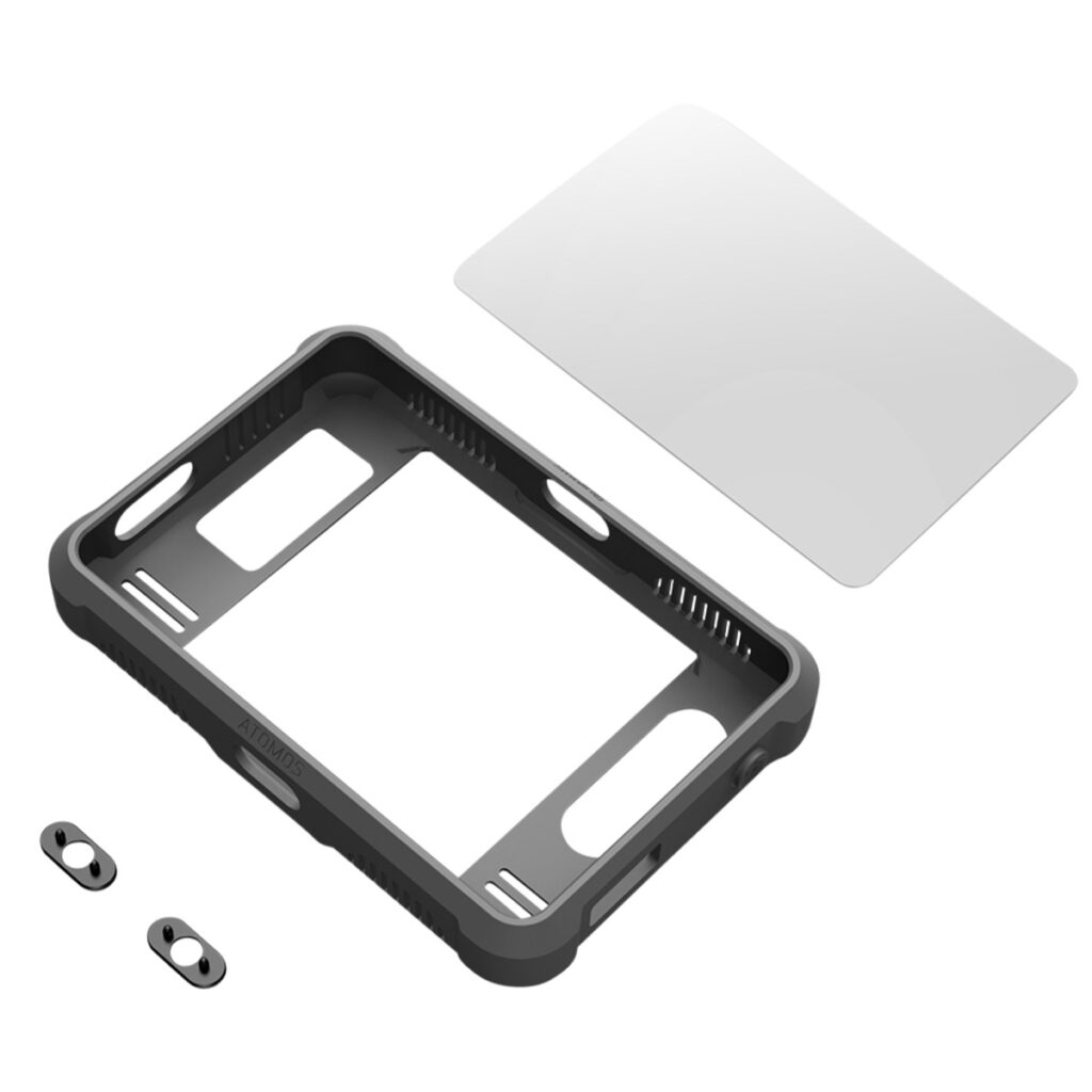 SmallRig-3454-2 SmallRig 3454 Silicon Case Kit Atomos Shinobi 7:lle sisältää mustan suorakulmaisen kotelon, läpinäkyvän näytönsuojan ja kaksi pientä metallikappaletta, jotka kaikki näkyvät erikseen valkoisella pohjalla.
