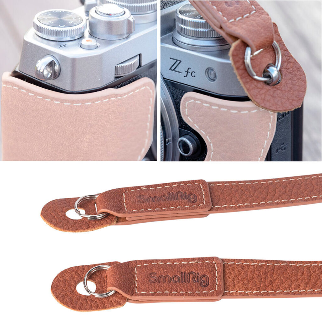 SmallRig-3485-2 Close-up of the SmallRig 3485 Leather Camera Neck Strap in brown, attached to a silver camera with embossed branding, detailed stitching and sturdy metal ring fasteners.
