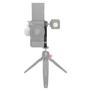 SmallRig-3523-4 Edestä katsottuna SmallRig 3523 Extension Grip for Sony ZV-E10, musta, kiinnitettynä pienellä jalustalla, ulkoinen valo kameran sivulla ja pystysuoraan asetettu kääntyvä näyttö; kamera ja jalusta näkyvät puoliksi läpinäkyvinä.