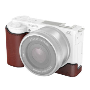 Valkoinen Sony Alpha ZV-E10 -peilitön kamera, jossa on suuri objektiivi ja jossa on SmallRig 3527 ruskea nahkainen puolikas kotelo, joka peittää kahvan alueen.