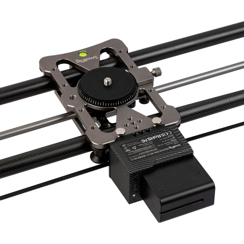 SmallRig-3542-3 SmallRig 3542 MS-10 Slider Motorized -mallin lähikuvassa näkyy sen metallivaunu yhdensuuntaisilla hiilikuitukiskoilla, ja sen alle on asennettu suuri musta akku, joka on suunniteltu kameran sujuvaan liikutteluun valokuvauksessa ja videokuvauksessa.