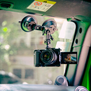 SmallRig-3566-4 SmallRig 3566 Portable Dual Suction Cup with Camera Mount SC-2K on kiinnitetty auton tuulilasiin ja tallentaa videon naisesta, jota näytetään sen ulos käännettävällä näytöllä, kun auton sisäkatto ja varoitustarrat näkyvät ja tausta on sumea.