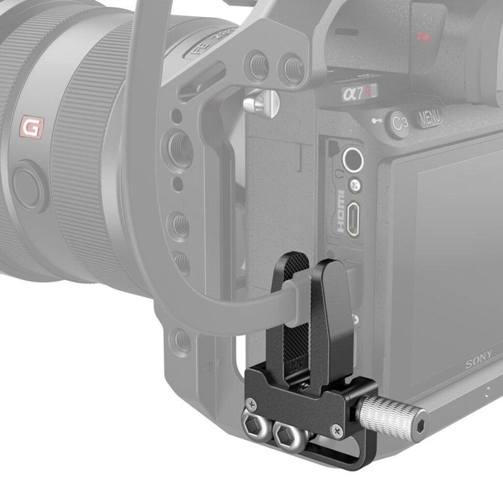 SmallRig-3637-4 Lähikuva SmallRig 3637 HDMI-kaapelikiinnittimestä, joka on kiinnitetty kameran häkkiin ja kiinnittää HDMI-kaapelin kameran kylkeen. Mustassa kiinnittimessä on metalliruuvit ja kuvioitu ote, joka estää kaapelin liikkumisen tai vahingoittumisen.