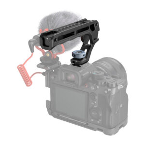 SmallRig-3764-4 The SmallRig 3764 Top Handle with Cold Shoe is mounted on top of the digital camera; it also has a microphone with a red twisted cable attached, and the camera body is faded to highlight the handle.