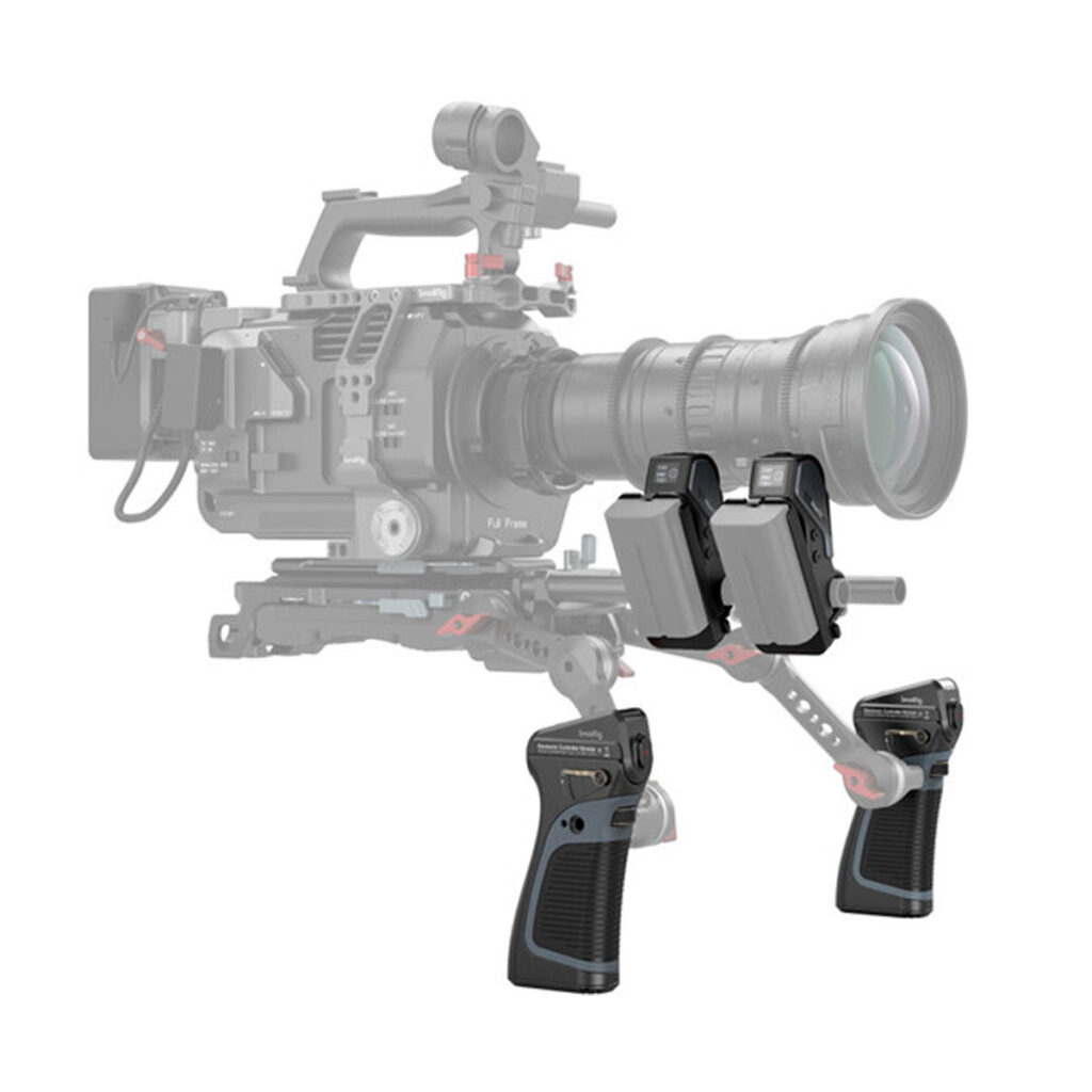 SmallRig-3782-4 Etualalla näkyy kaksi SmallRig 3782 Magic Fiz Wireless Follow Focus Handgrip Kit -käsikahvasarjaa, joissa on painikkeita ja säätimiä; taustalla näkyy häivytettynä ammattimainen videokamera, jossa on suuri objektiivi ja lisävarusteita.