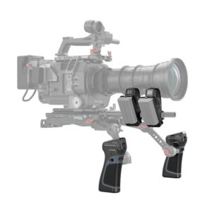 SmallRig-3782-4 Etualalla näkyy kaksi SmallRig 3782 Magic Fiz Wireless Follow Focus Handgrip Kit -käsikahvasarjaa, joissa on painikkeita ja säätimiä; taustalla näkyy häivytettynä ammattimainen videokamera, jossa on suuri objektiivi ja lisävarusteita.