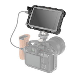 SmallRig-3788-2 Musta SmallRig 3788 Cage Kit for Atomos Ninja V/V+, jossa on liitetty kaapeli, on asennettu digitaalikameran päälle, jonka toisella puolella on puinen kahva; kameran runko on osittain läpinäkyvä.