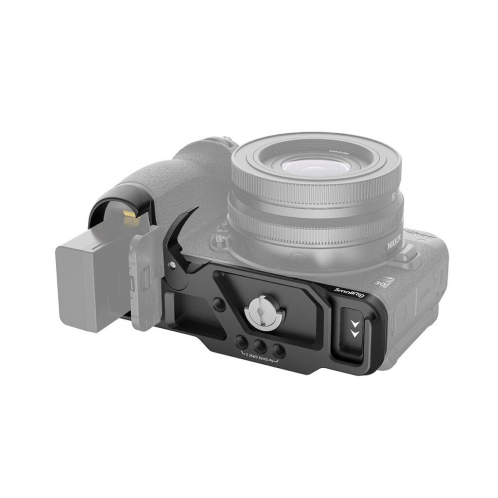 SmallRig-3857-4 SmallRig 3857 Baseplate for Nikon Z30 on asennettu kameran ja objektiivin alle, jolloin kiinnike korostuu. Akkulokero on auki, ja siihen on asetettu osittain akku, ja kameran runko on korostuksen vuoksi osittain harmaalla.