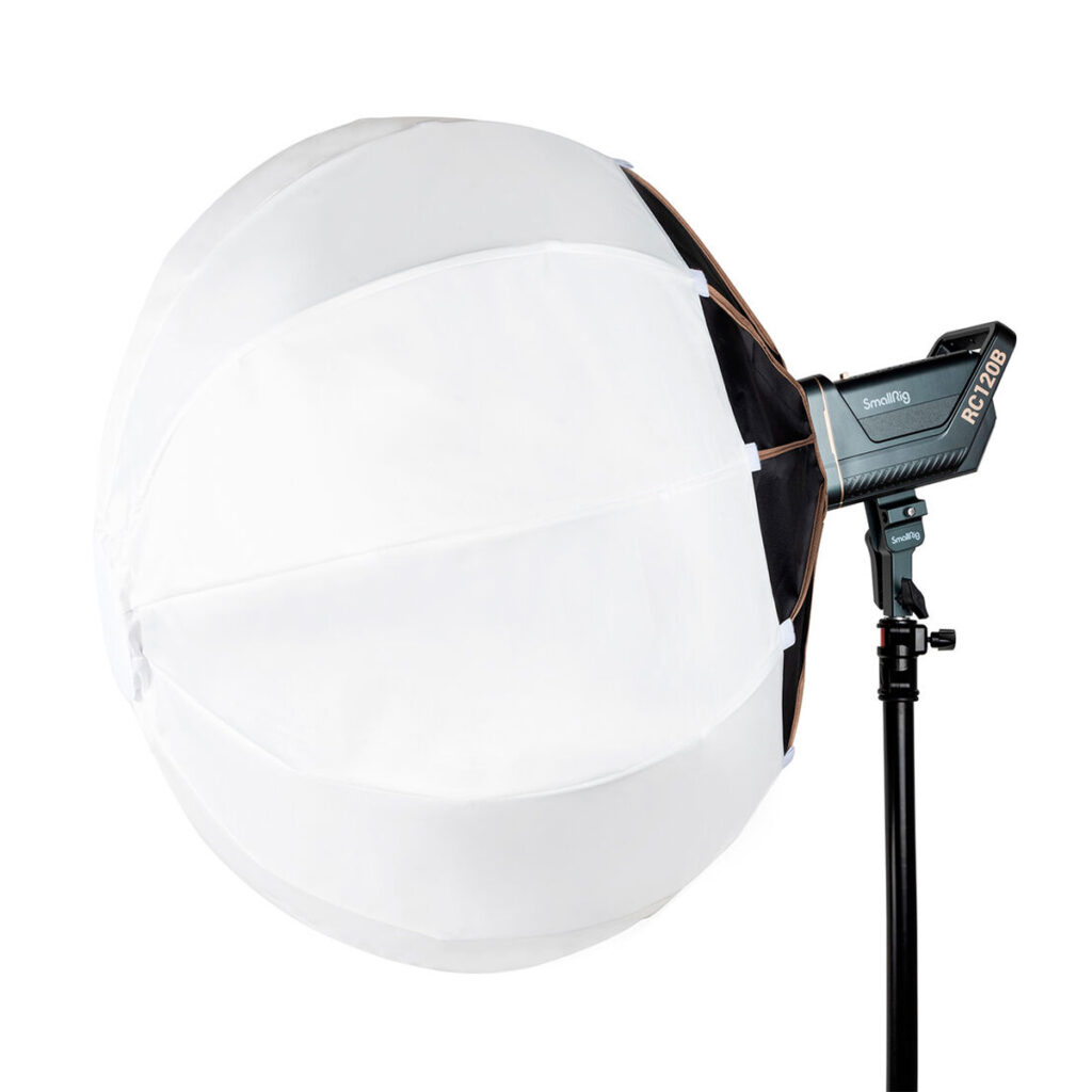 SmallRig-3932-2 SmallRig 3932 RA-L90 Lantern Softbox, suuri ja valkoinen, jossa on pallomainen diffuusori, on kiinnitetty studiovaloon mustalla jalustalla. Valonlähde ja Revolabin tuotemerkki näkyvät oikealla puolella.