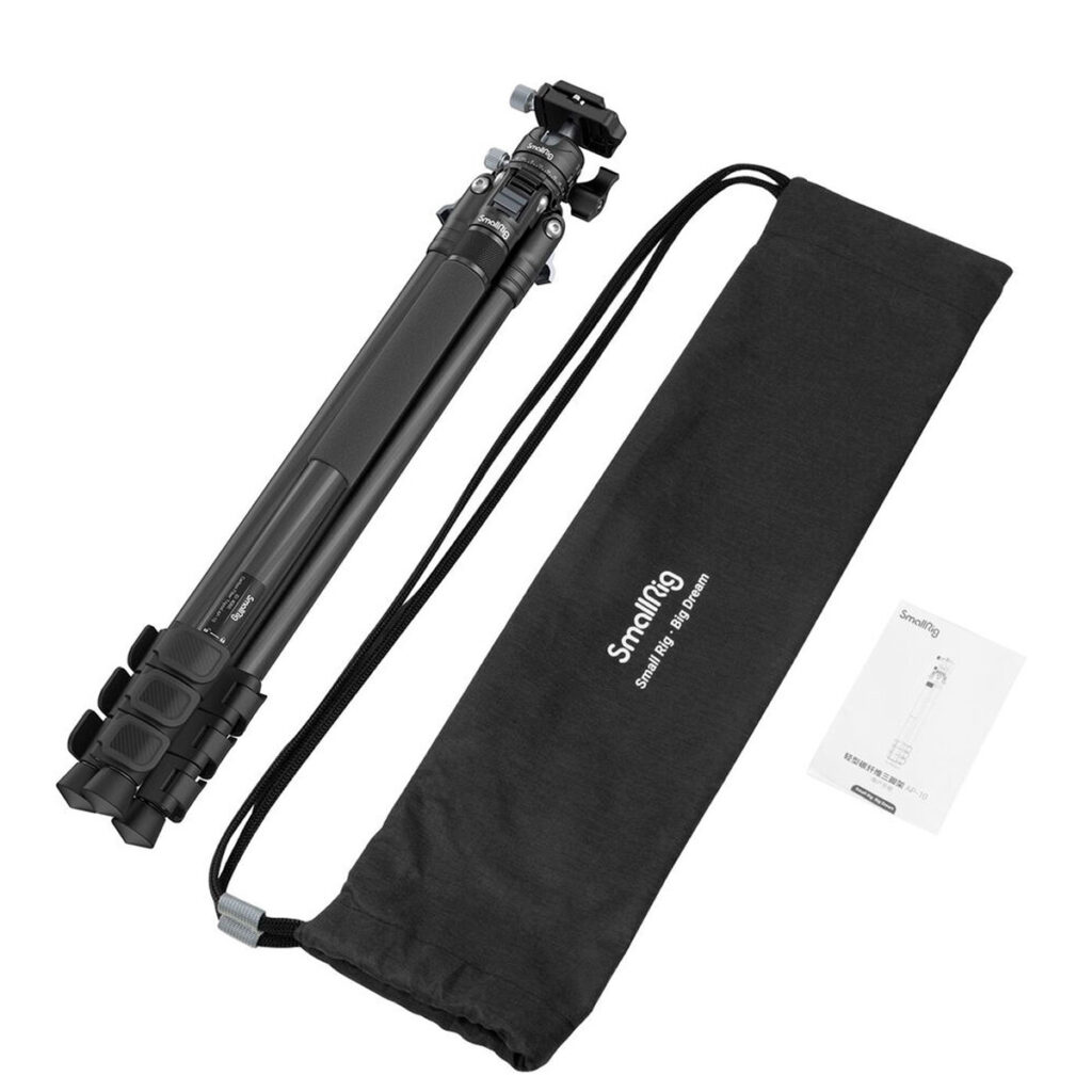 SmallRig-4060-5 SmallRig 4060 Carbon Fiber Tripod Kit AP-10 -hiilikuitu kolmijalka näkyy taitettuna mustan kiristysnyörillä varustetun kantolaukun ja käyttöohjeen vieressä, kaikki valkoisella pohjalla.