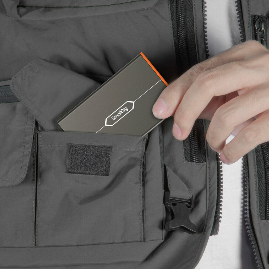 SmallRig-4107-5 Hand put the SmallRig 4107 Memory Card Case for Sony CFexpress Type A in the zipped pocket of the grey jacket.