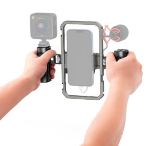 SmallRig-4121-4 The person is holding the SmallRig 4121 All-In-One Video Kit Mobile Basic with both hands, with a smartphone attached in the middle, a small camera on the left and an external microphone on the right.