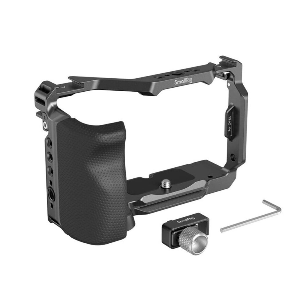SmallRig-4257-5 SmallRig 4257 Cage Kit Sony ZV-E1:lle, kuvassa mustana kuvioidulla otteella, sisältää hopeisen kiristysnupin ja pienen kuusiokoloavaintyökalun, kaikki valkoisella pohjalla.