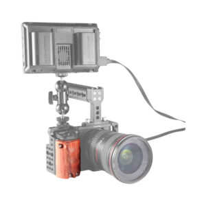 SmallRig_1970_002 Sony A6500 -kamera, jossa on SmallRig 1970 Wooden Handgrip -käsikahva ja joka on asennettu metallihäkkiin, jossa on eteenpäin suunnattu objektiivi ja suuri ulkoinen näyttö, joka on liitetty kaapelilla.