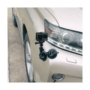 SmallRig_Cage_for_DJI_Osmo_Action_3_4119_007 The SmallRig 4119 Cage for DJI Osmo Action 3 / 4 is attached to the side of a beige car near the front wheel and headlights with a black suction cup mount. The car is parked on a paved surface.