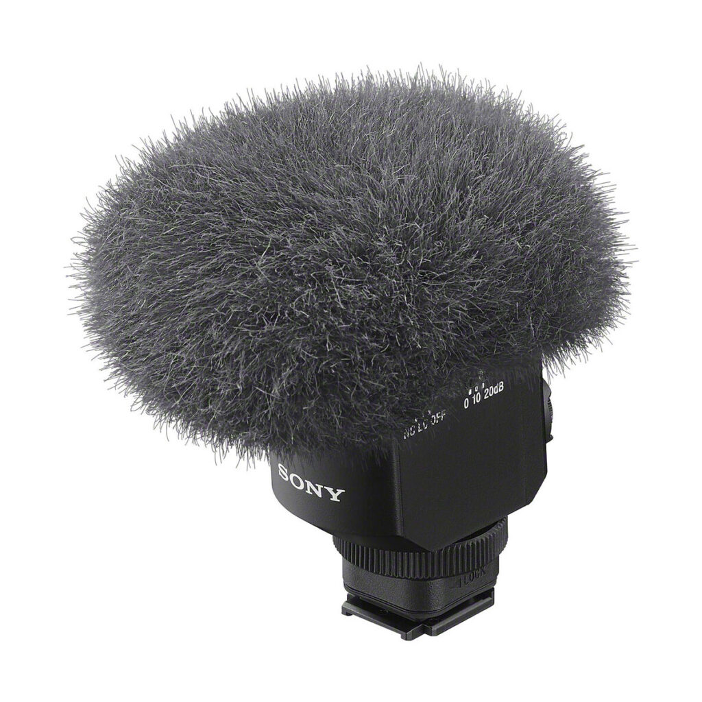 sony_ecm_m1_03 Close-up of a Sony ECM-M1 microphone with a fluffy grey windscreen to reduce wind noise during audio recording, and a black base with clearly marked controls.