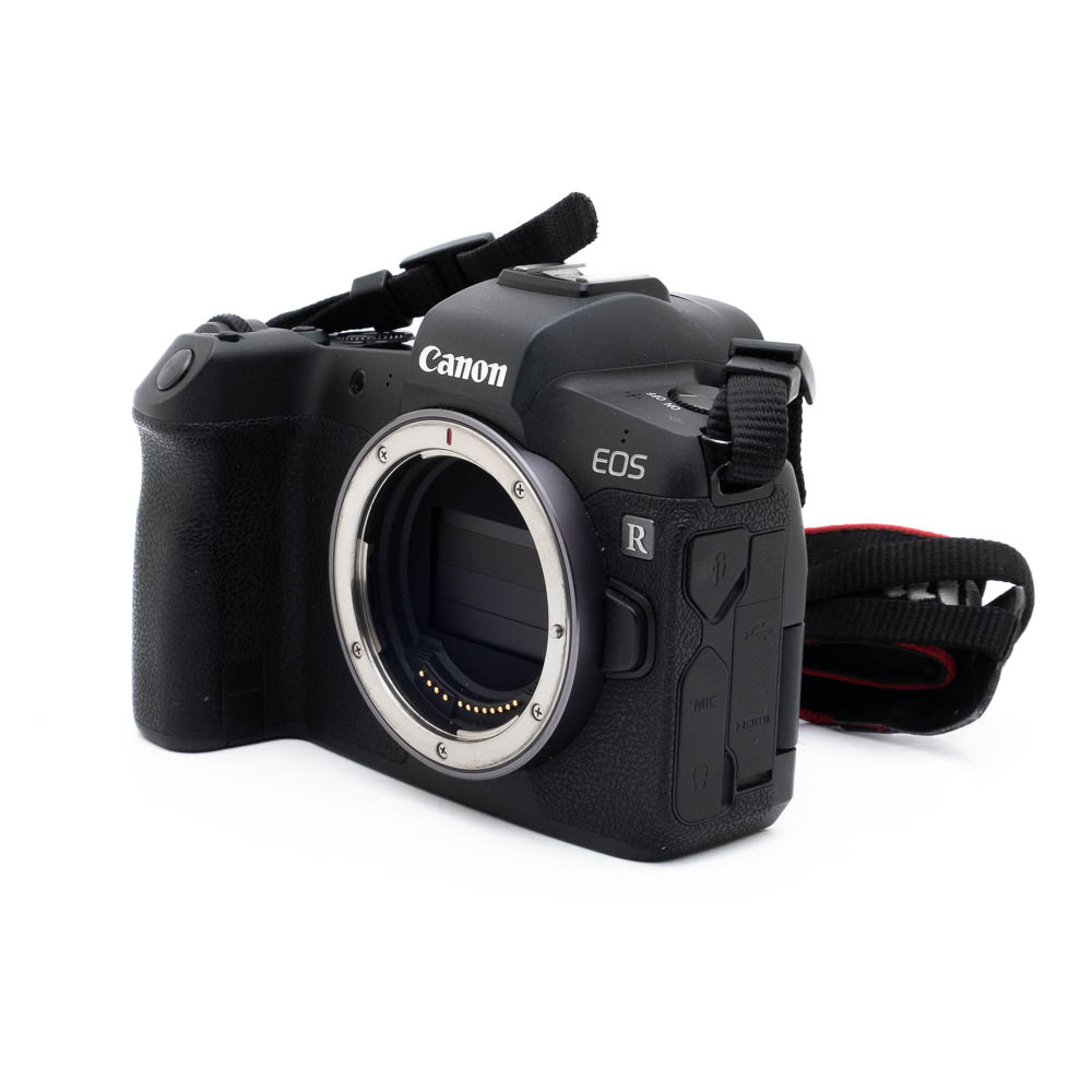 Canon EOS R (SC 63000) - Käytetty peilitön kamerarunko, musta, kuvassa ilman objektiivia, objektiivin kiinnitys ja kenno; osa kameran hihnasta on näkyvissä.