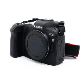 Canon Eos R-2 Canon EOS R (SC 63000) - Käytetty peilitön digikamera, musta, pelkkä runko, näkyy edestä ja oikealta puolelta kuvioidulla kahvalla ja punaisella reunustetulla kaulahihnalla.
