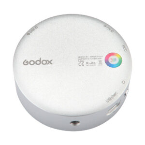 Godox_R1_003 Godox R1 on pyöreä, hopeinen laite, jonka pinnalla on merkittyjä painikkeita, portteja, RGB-valon merkkivalo ja painettu teksti sertifiointimerkinnöillä.