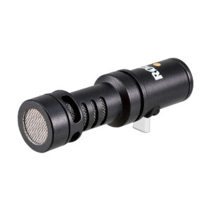 Rode_Video_Mic_Me-C_003 Musta sylinterimäinen Rode Videomic ME-C -mikrofoni, jossa on metalliverkkosäleikkö ja tuuletetut sivut, kiinnitettynä hopeiseen pidikkeeseen valkoista taustaa vasten.