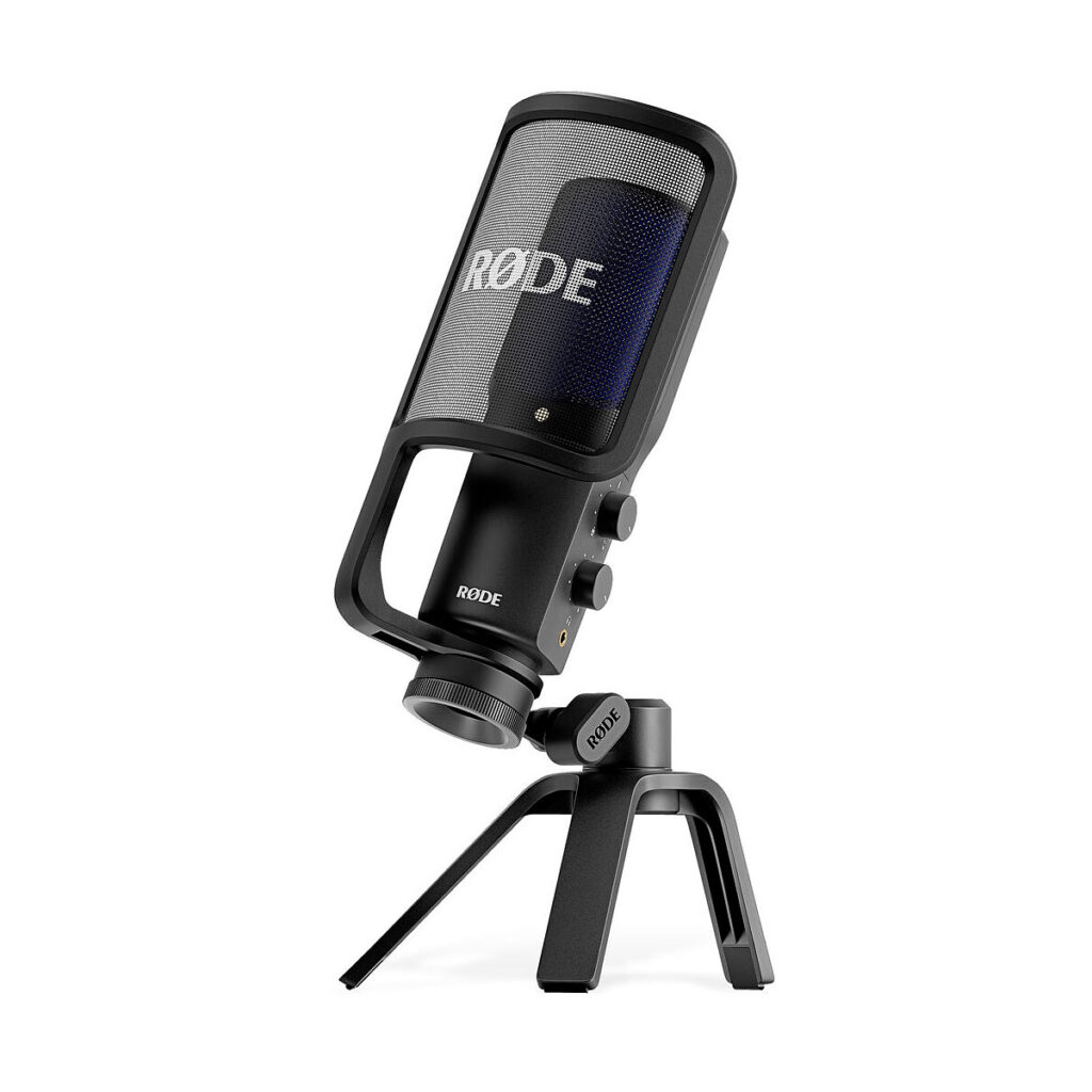 Rode_Video_NT-USB+_004 Musta Rode Videomic ME-C -pöytämikrofoni, jossa on sisäänrakennettu pop-suodatin ja säädettävä jalusta, kuvassa edestä vasemmalta. Mikrofonissa on kaksi säätönuppia ja "Rode"-brändinimi sekä ritilässä että jalustassa.
