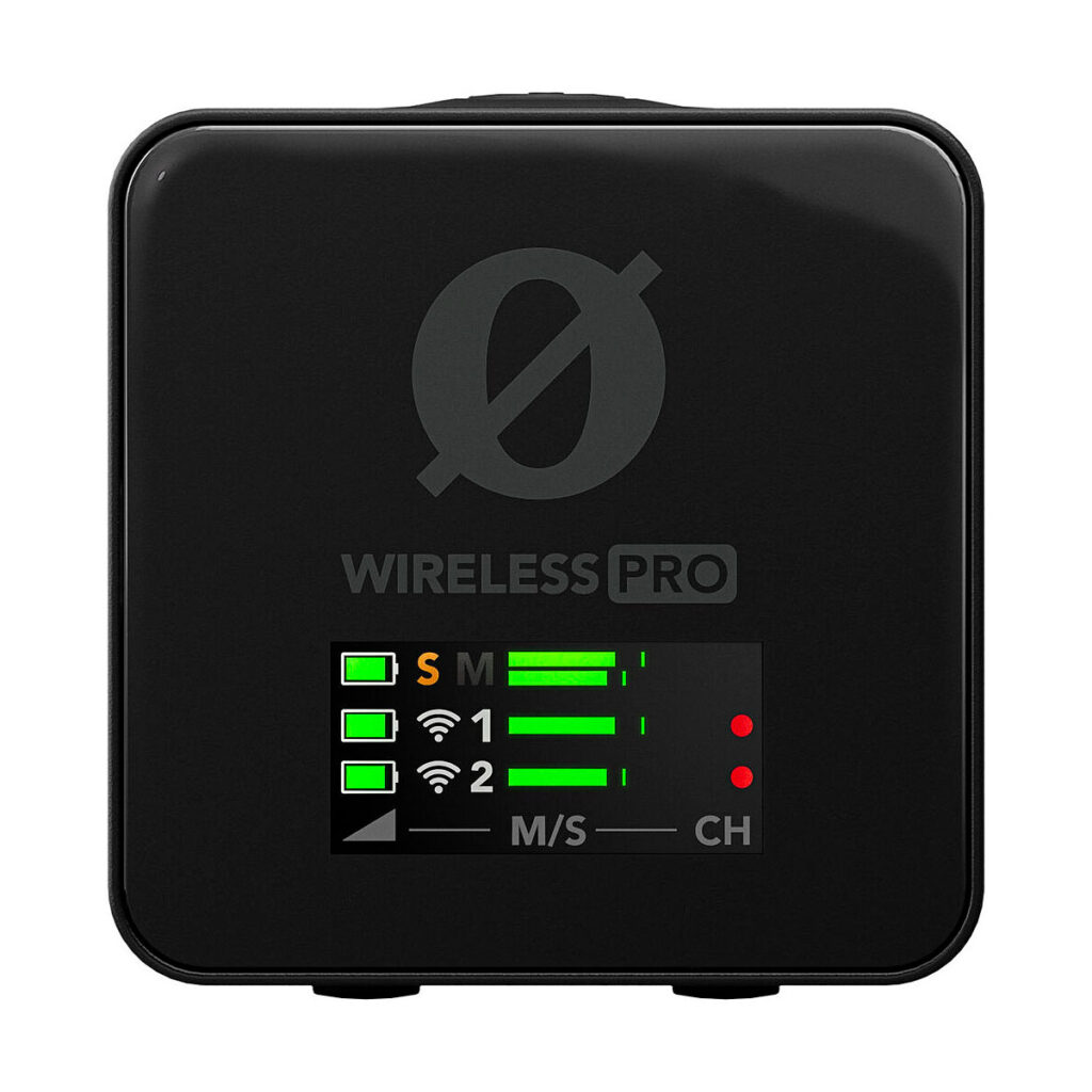 Rode_Wireless_Pro_003 Rode Wireless Pro -langaton mikrofonijärjestelmä on musta langaton audiolaite, jonka näytössä on vihreät signaalipalkit, paristokuvakkeet ja punaiset kanavamerkit. Näytön yläpuolella on WIRELESS PRO -merkintä ja pyöreä logo.