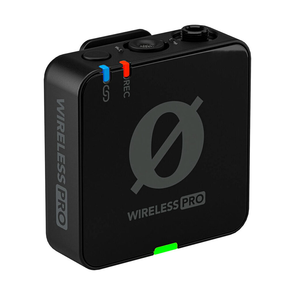Rode_Wireless_Pro_004 Rode Wireless Pro -langaton mikrofonijärjestelmä on musta, suorakaiteen muotoinen langaton lähetin, jossa on pyöreä logo, punaisilla ja sinisillä merkinnöillä varustetut sivuportit ja vihreä merkkivalo pohjassa.