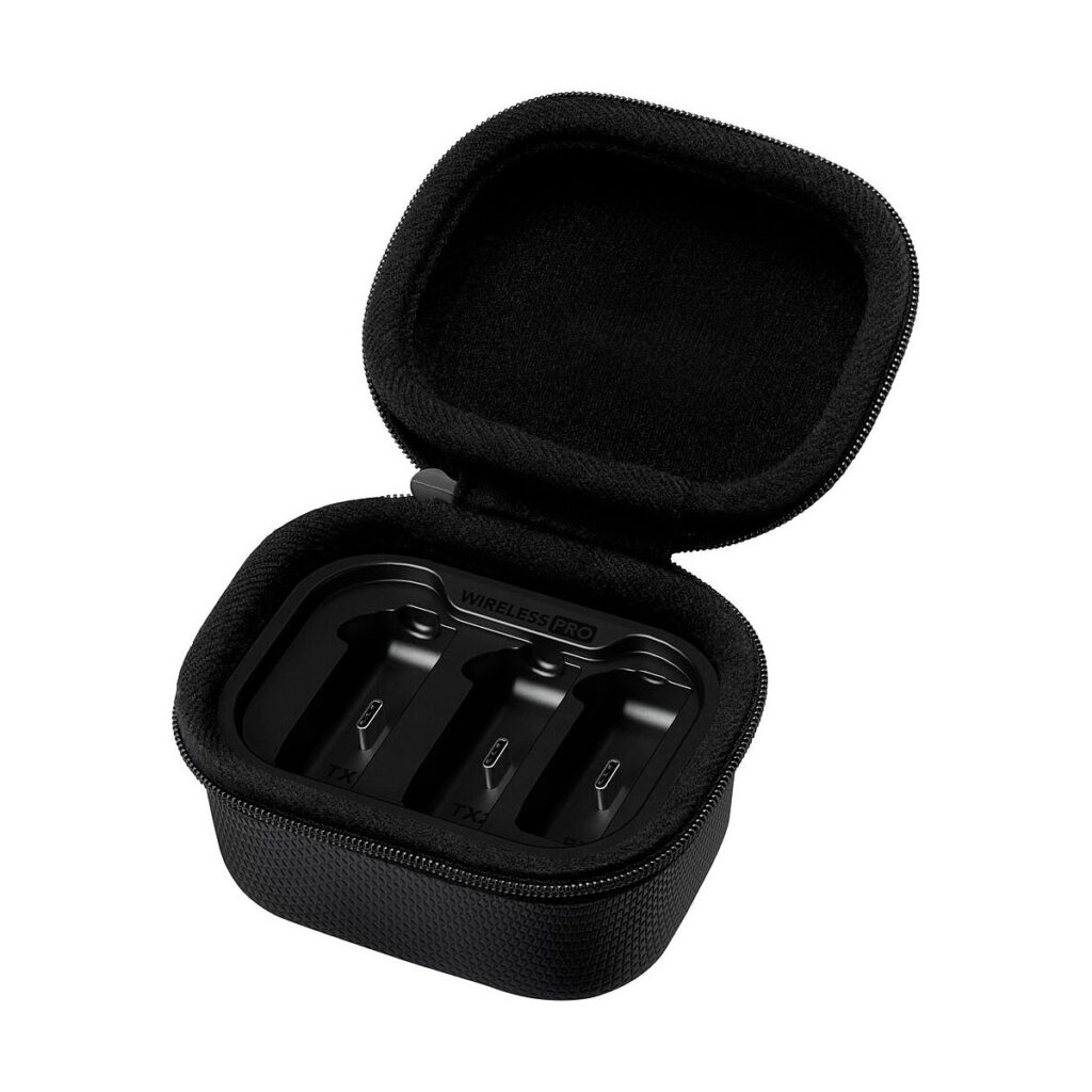 Rode_Wireless_Pro_009 Rode Wireless Pro -langaton mikrofonijärjestelmä -laitteen musta vetoketjullinen kantokotelo näkyy avattuna valkoisella pohjalla, ja sen sisällä on kolme latauspaikkaa, joihin on merkitty TX ja RX. Kotelo ei sisällä kuulokkeita.