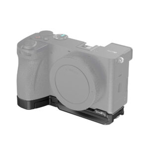 SmallRig_Baseplate_for_Sony_Alpha_6700_4338_001 Kamera, jossa on objektiivin kiinnityssuojus, on kuvassa kiinnitettynä SmallRig 4338 Baseplate for Sony Alpha 6700 -jalustaan, joka muodostaa L-kirjaimen muotoisen kiinnikkeen kameran vasemman alakulman ympärille. Kameran runko on osittain läpinäkyvä.