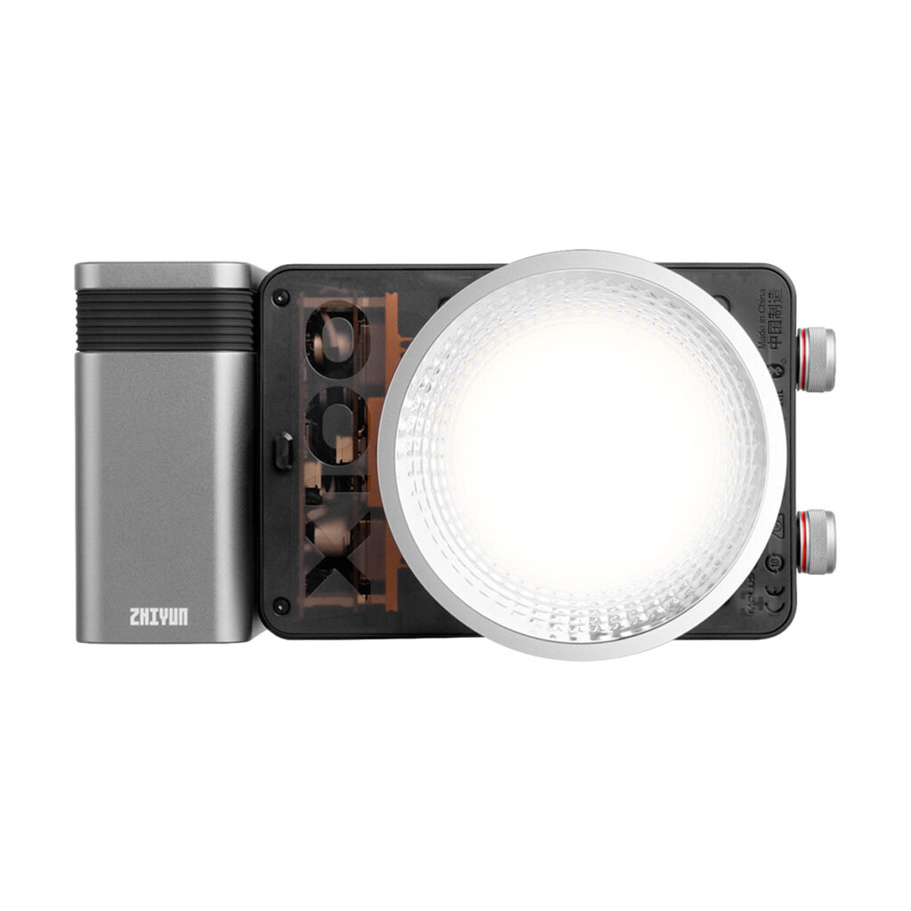 Zhiyun_Molus_X100_004 The Zhiyun LED Molus X100 COB Light Pro is a compact, rectangular LED video light with a large circular diffuser, a metallic grey battery pack on the left side with Zhiyun branding and adjustment wheels on the right side.