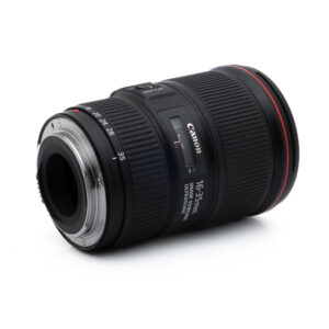 Canon EF 16-35mm f/4 L IS USM - Käytetty laajakulmaobjektiivi makaa kyljellään, objektiivikiinnitys vasemmalla, ja sen musta runko, zoomausrengas ja erottuva punainen L-sarjan rengas etupuolen lähellä.