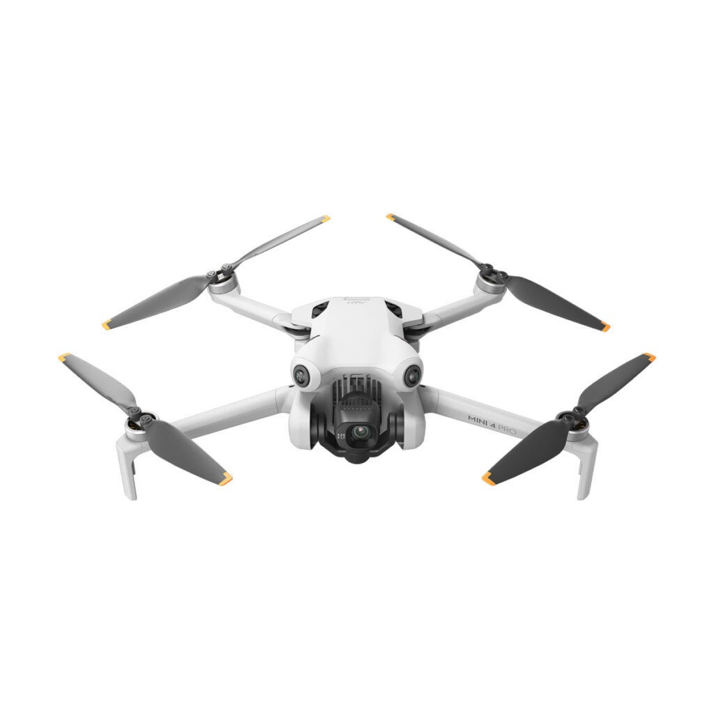 DJI_mini4pro_003 DJI Mini 4 Pro -lennokki näkyy valkoisella taustalla, ja siinä on etukamera, taitettavat käsivarret sekä mustat ja harmaat potkurit, joissa on keltaiset kärjet.