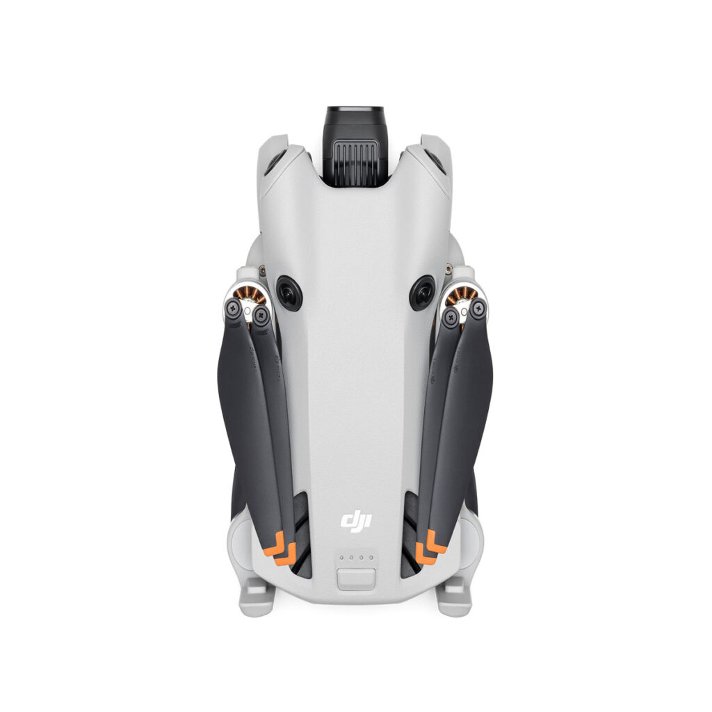 DJI_mini4pro_005 DJI Mini 4 Pro -lennokki näkyy taitettuna ylhäältä alaspäin, ja siinä on harmaa runko, mustat potkurit, etukamera ja DJI:n logo ylhäällä valkoista taustaa vasten.