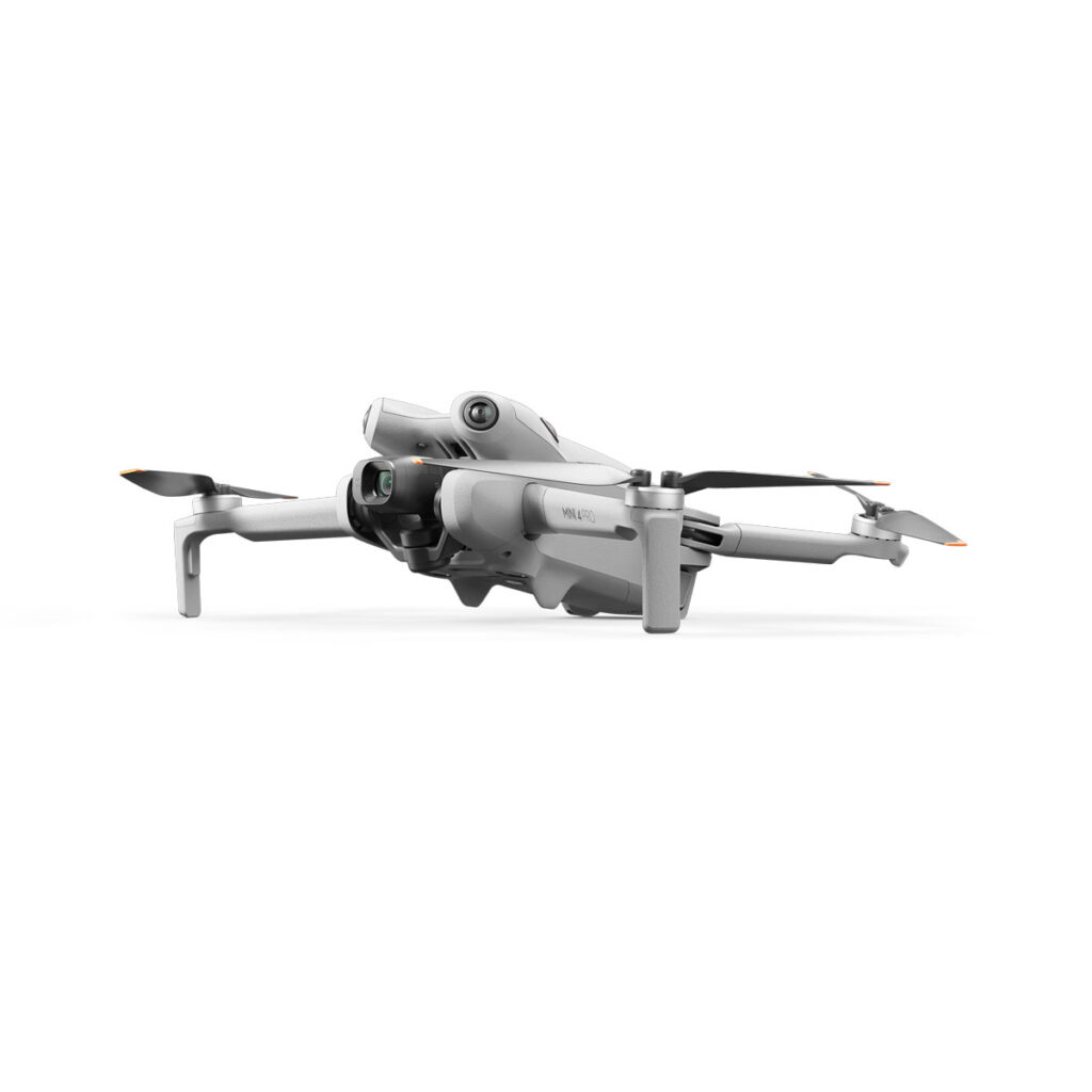 DJI_mini4pro_007 DJI Mini 4 Pro -lennokki on tyylikäs valkoinen nelikopteri, jossa on etukamera, kokoontaitettu laskuteline ja neljä potkuria valkoista taustaa vasten.