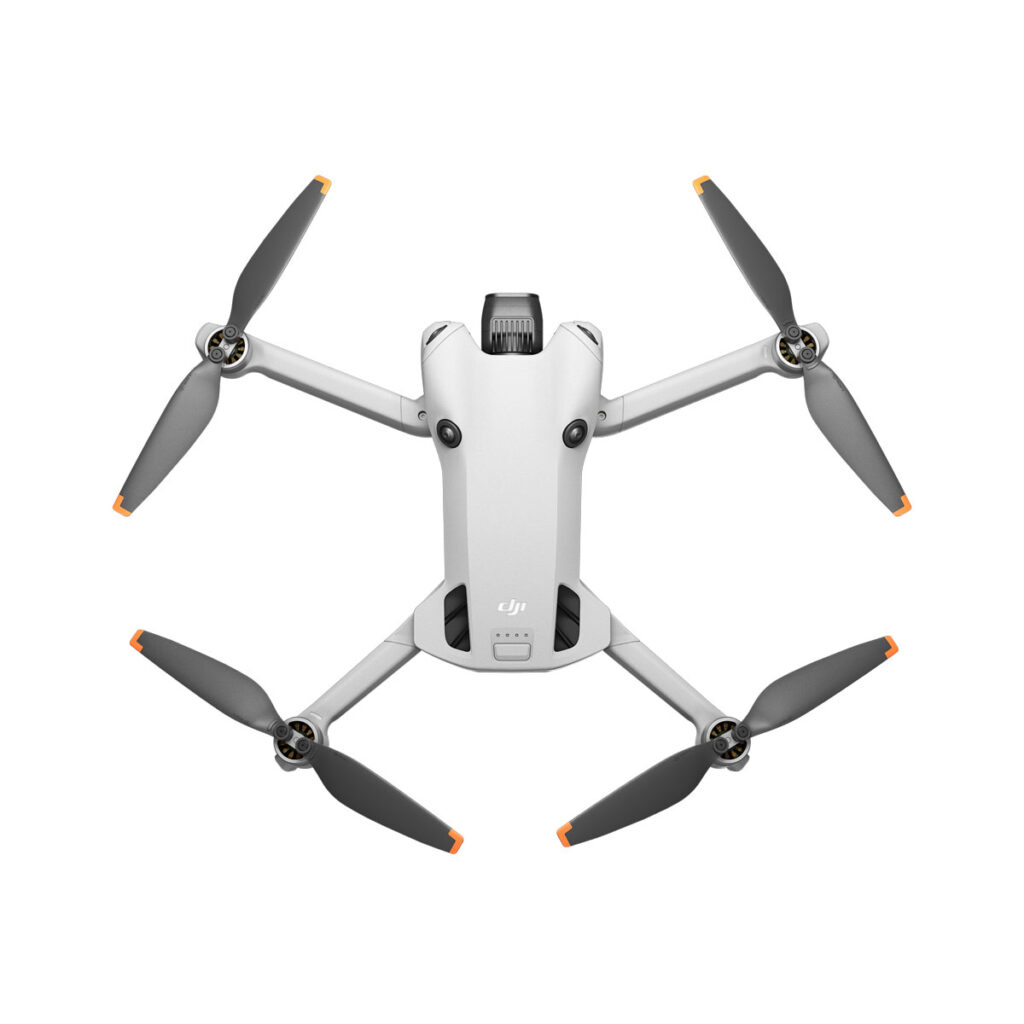 DJI_mini4pro_009 DJI Mini 4 Pro -lennokki on harmaa, siinä on neljä ulospäin suuntautuvaa potkuria, joissa on oranssit kärjet, ja siinä on edestä katsottuna etukamera.