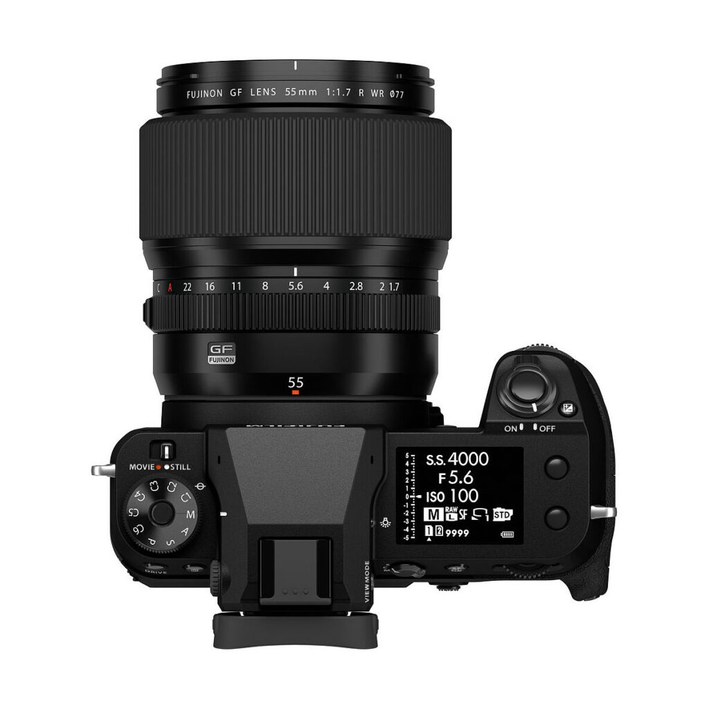 Ylhäältä katsottuna musta Fujifilm-kamera, johon on kiinnitetty Fujinon GF 55mm f/1.7 R WR -objektiivi, jossa on säätöpyörät, painikkeet ja digitaalinen näyttö, joka näyttää kameran asetukset.