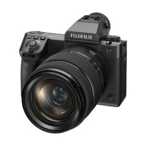 A Fujifilm GFX 100 II -järjestelmäkamera, musta, suuri zoom-objektiivi kiinnitettynä, kuvattuna viistosti valkoista taustaa vasten. Nyt 500€ alennus!.