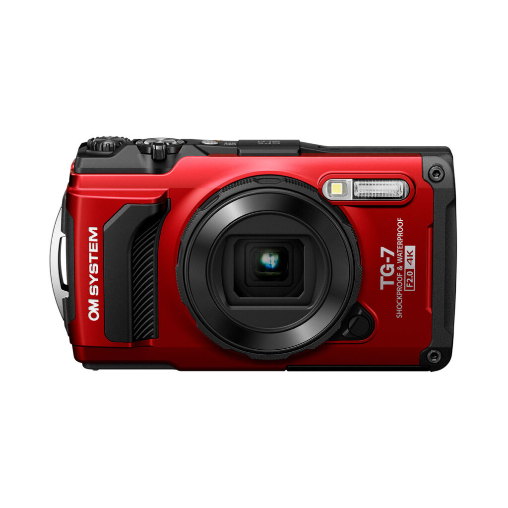 Olympus_TG-7_PUN_002 OM System Tough TG-7 -kompaktikamera, punainen, näytetään edestä sen objektiivi, salama, painikkeet ja tarrat korostavat ominaisuuksia, kuten "iskunkestävä" ja "vedenpitävä".