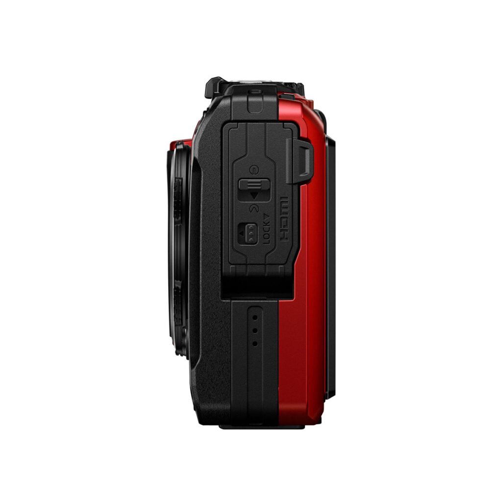 Olympus_TG-7_PUN_004 Sivunäkymä OM System Tough TG-7 -kompaktikamera, punainen, osoittaa sen suljettu HDMI ja USB-portit selkeät tarrat, kuvioitu kahva, ja osa objektiivin näkyvissä. Kamera on punainen ja musta valkoista taustaa vasten.