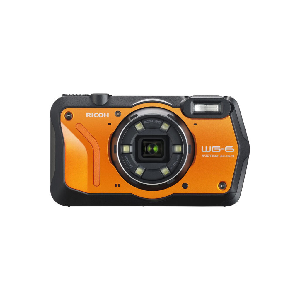 Ricoh_WG-6_001 Kestävä Ricoh WG-6 Orange Kompaktikamera on kuvattu eteenpäin, ja sen etupuolella on keskellä oleva objektiivi, salama sen yläpuolella ja "WG-6" sekä "WATERPROOF 20M/65.6FT" näkyvissä.